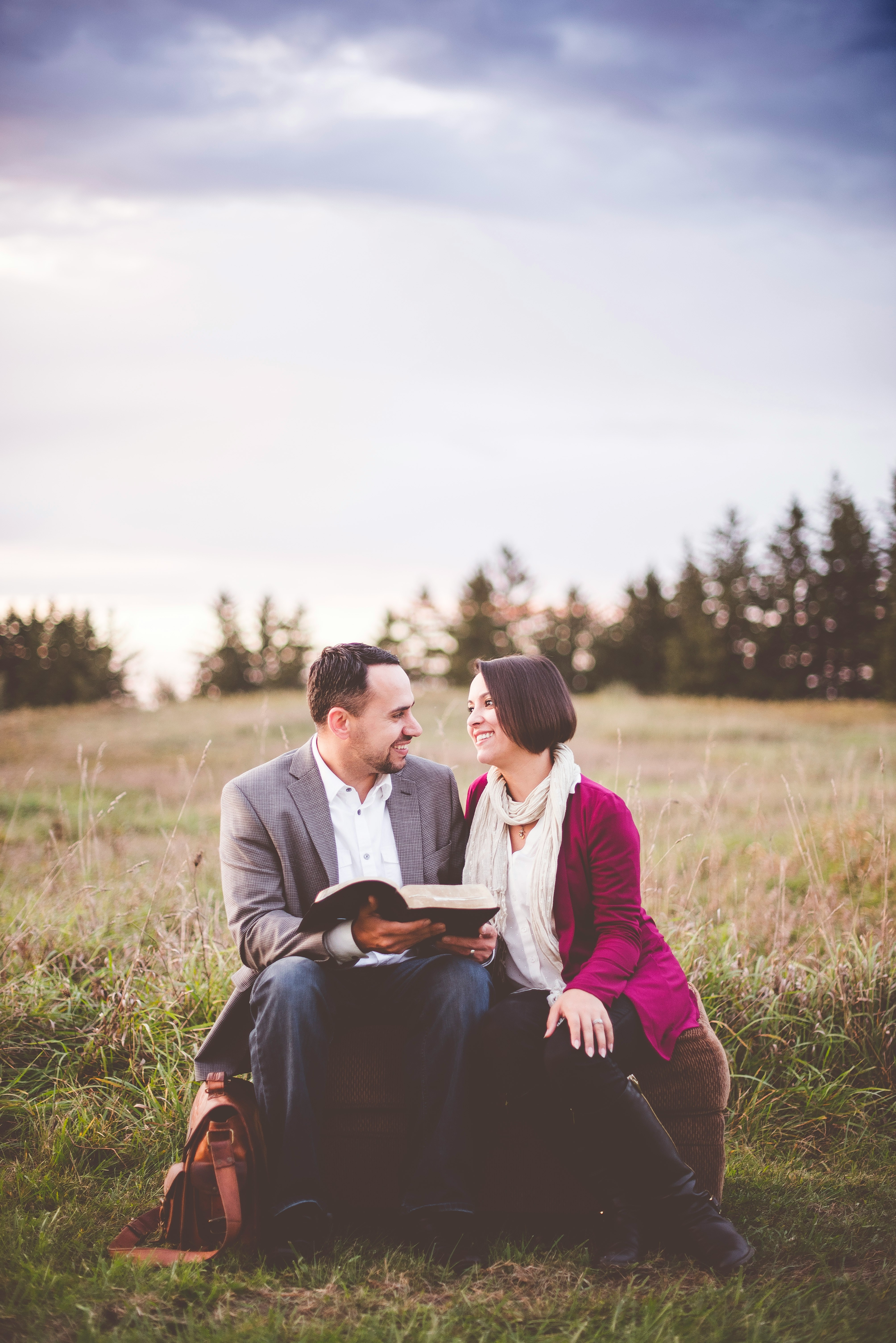 Engaged couple reading Scripture together outdoors